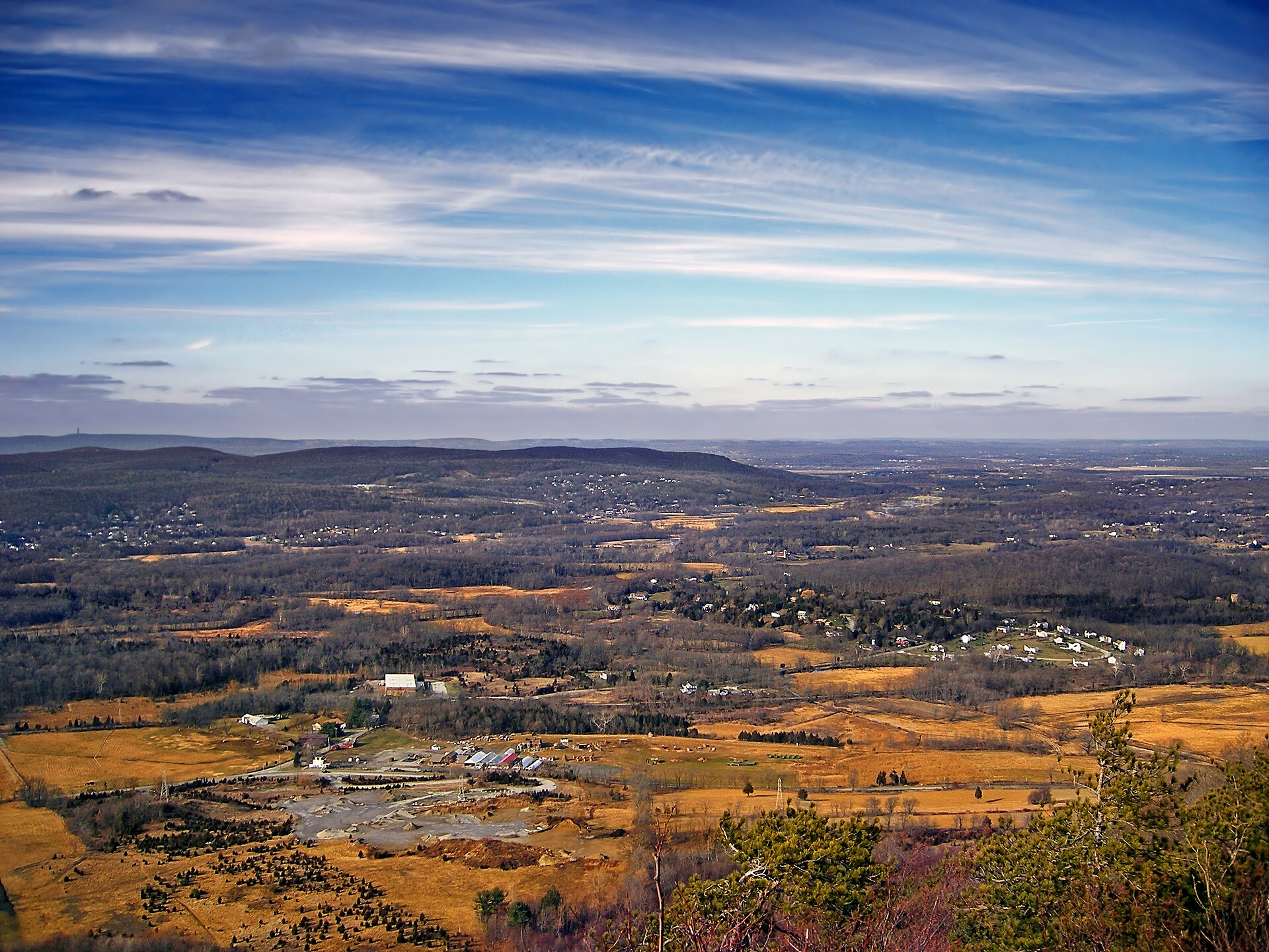 The Vernon valley seen from Pinwheel Vista in late autumn, with tan farm fields, wooded ridges and a long escarpment on the horizon