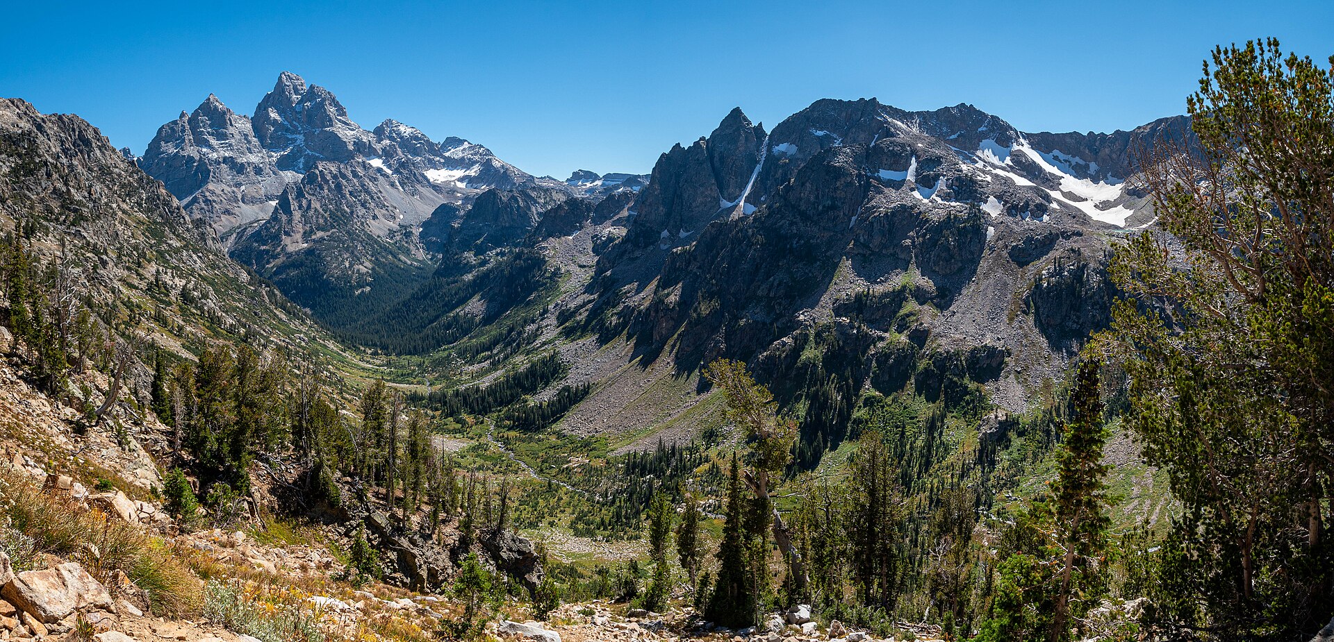 Cascade Canyon in Grand Teton National Park seen from Paintbrush Divide, with the Grand Teton and snow-streaked peaks rising above a green glacial valley