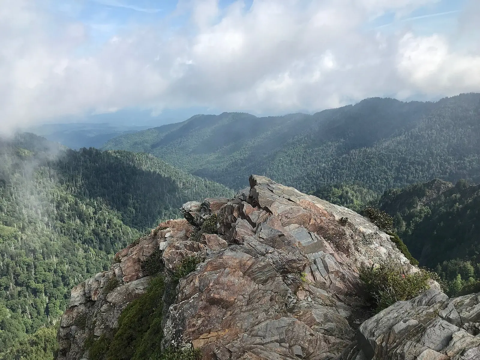 The bare rock spine of Charlies Bunion in the Great Smoky Mountains, cloud drifting past forested ridges receding into haze behind it