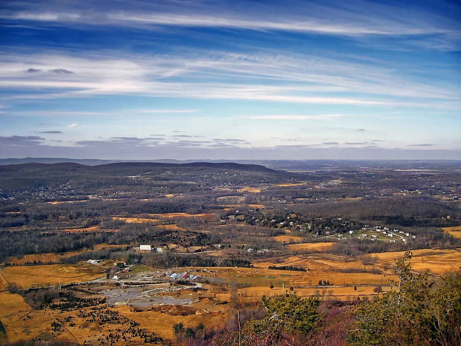 The Vernon valley seen from Pinwheel Vista in late autumn, with tan farm fields, wooded ridges and a long escarpment on the horizon