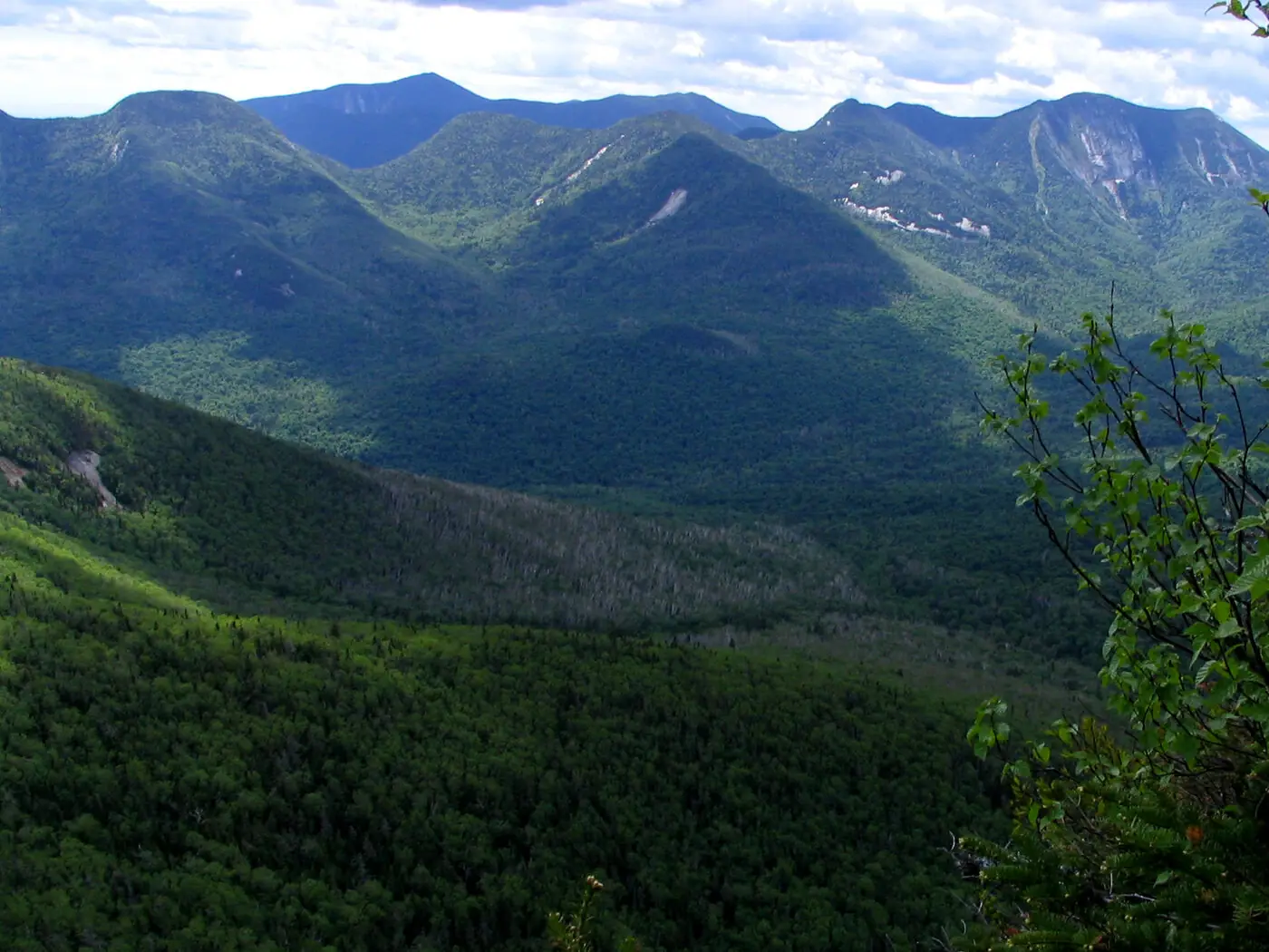 The Great Range in the Adirondack High Peaks in summer, a line of forested summits with pale rock slides on their flanks above a deep green valley
