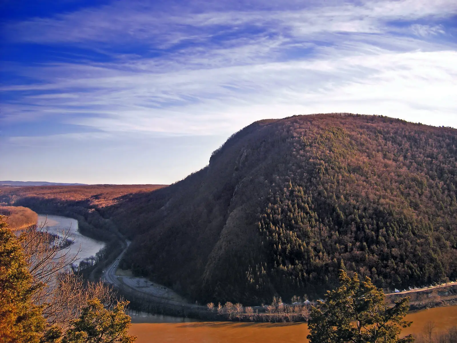 The bare late-autumn ridge of Mount Minsi rising steeply above the Delaware River and Route 611, seen from a rock lookout on Mount Tammany across the river in New Jersey