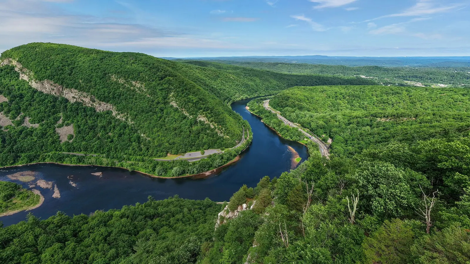 Aerial view of the Delaware Water Gap, the river bending through a deep notch between forested ridges with Interstate 80 running along the far bank in high summer