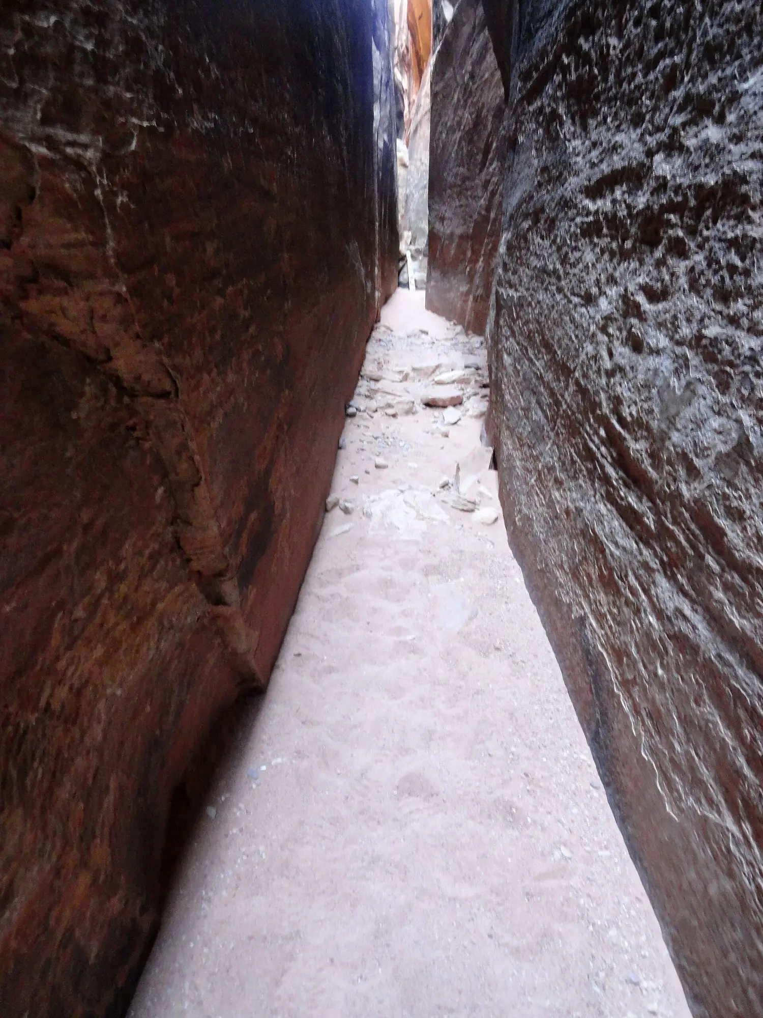 A sandy corridor barely wider than a person running between two vertical walls of red sandstone on the Joint Trail in the Needles district of Canyonlands
