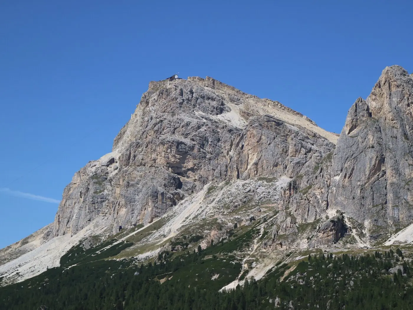 The pale limestone bulk of Lagazuoi Piccolo in the Dolomites against a deep blue sky, with the small square outline of Rifugio Lagazuoi visible on the summit ridge